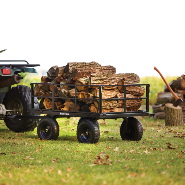 Gorilla utility cart filled with logs, featuring black metal frame and off-road tires.