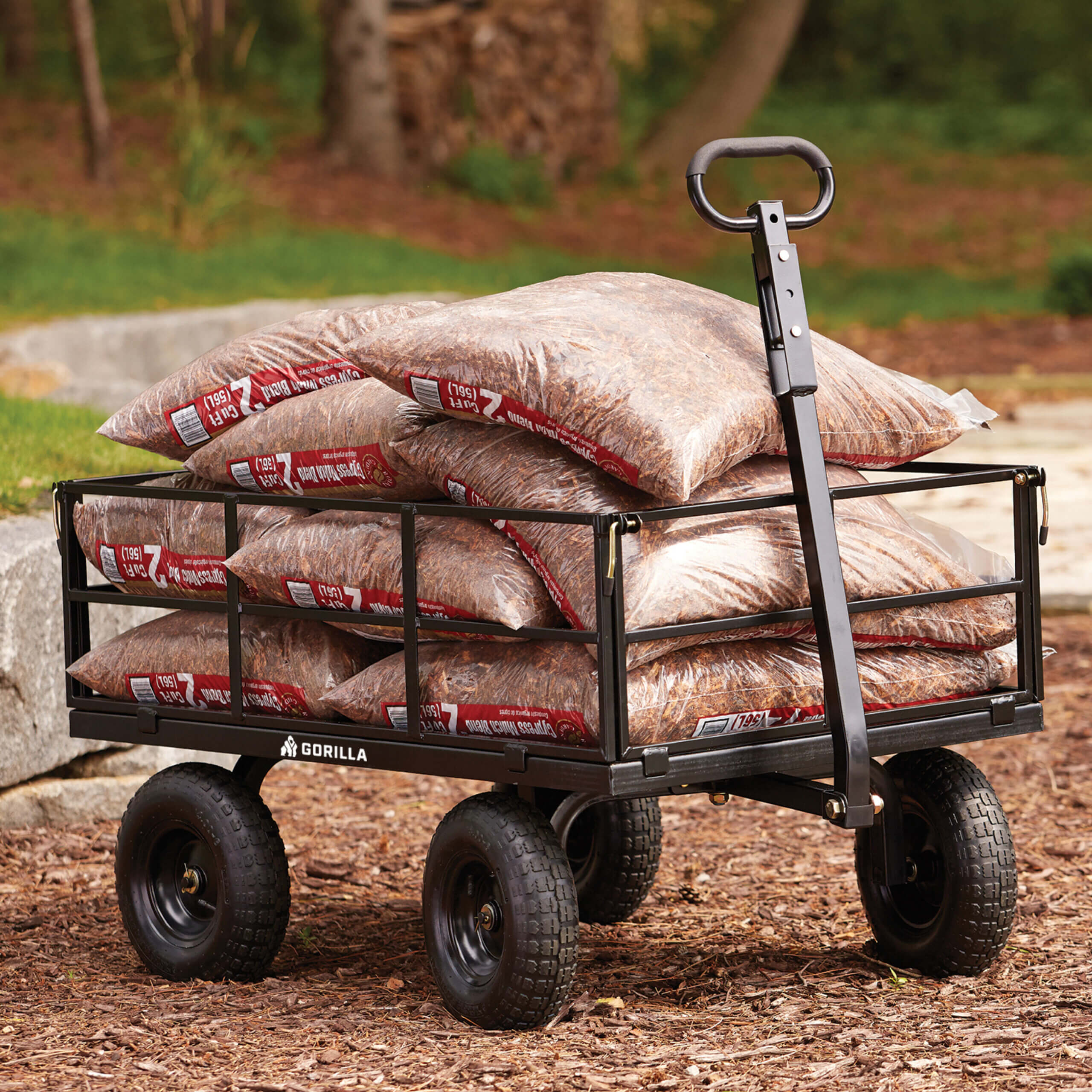 Black utility cart labeled "GORILLA" carrying bags of mulch outdoors.