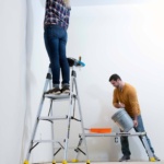Person using Gorilla Made ladder, another with a bucket nearby on a platform.