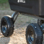 Close-up of black Gorilla utility cart wheels on gravel path.