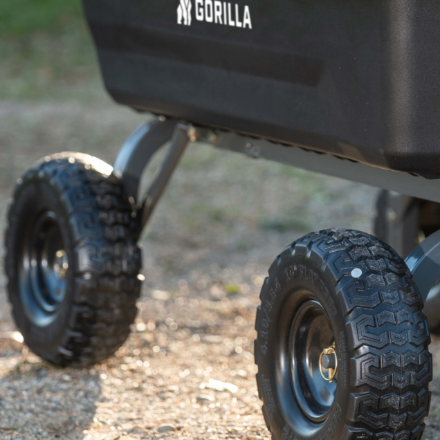 Close-up of black Gorilla utility cart wheels on gravel path.