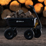 Black Gorilla utility cart filled with firewood, large wheels, logs in background.