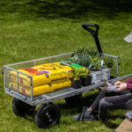 Gorilla Made cart with potting mix and plants on grass, person adjusting glove.