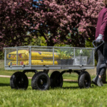 A person pulls a Gorilla Made utility cart loaded with yellow bags and plants.