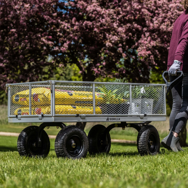 A person pulls a Gorilla Made utility cart loaded with yellow bags and plants.