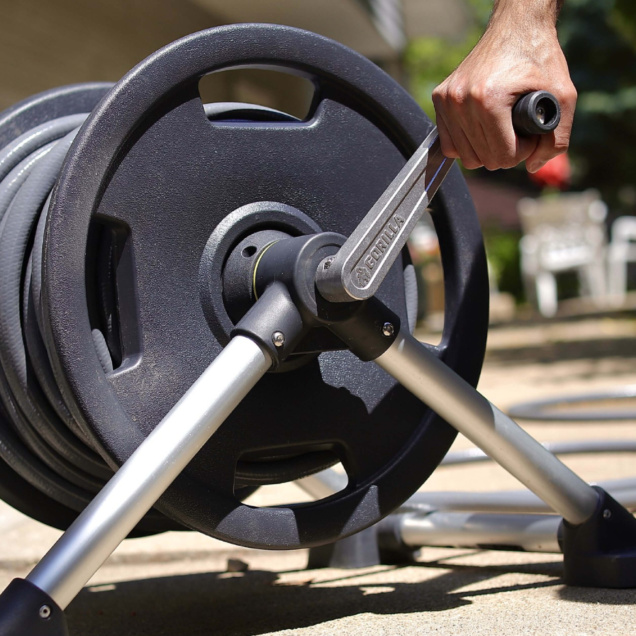 A Gorilla Made hose reel with gray and metallic design, held by a hand.