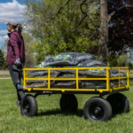 Person pulling a yellow Gorilla Made utility cart loaded with garden supplies.