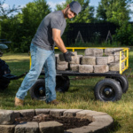 Person uses Gorilla Made's utility cart with yellow frame to transport gray bricks.