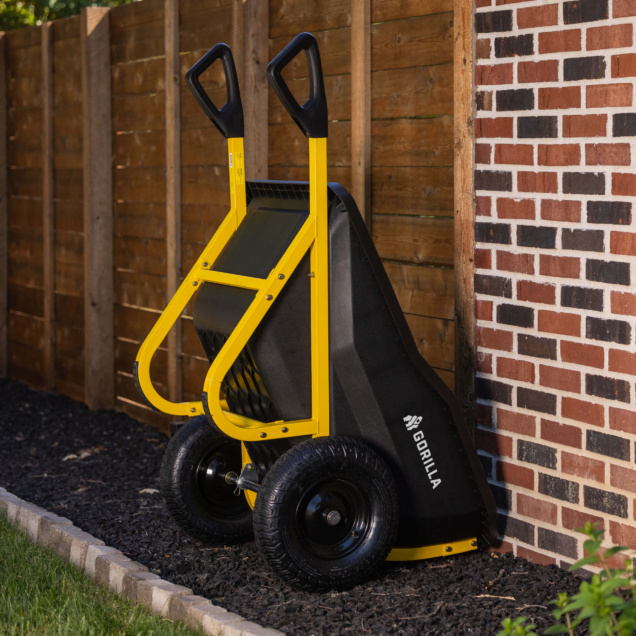 Yellow and black Gorilla hand truck leaning against a brick wall.