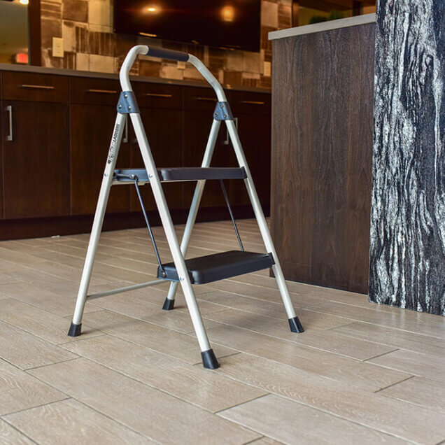 Silver step ladder with black steps in a modern kitchen setting.