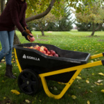 Gorilla cart filled with apples on grass, featuring yellow handles and black wheels.