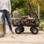 Gorilla utility cart with firewood, black mesh sides, and logo on a concrete path.