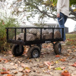 Black Gorilla utility cart filled with stones on a path amidst autumn leaves.