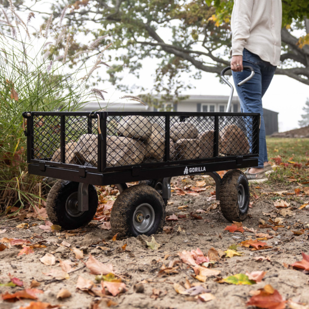 Black Gorilla utility cart filled with stones on a path amidst autumn leaves.
