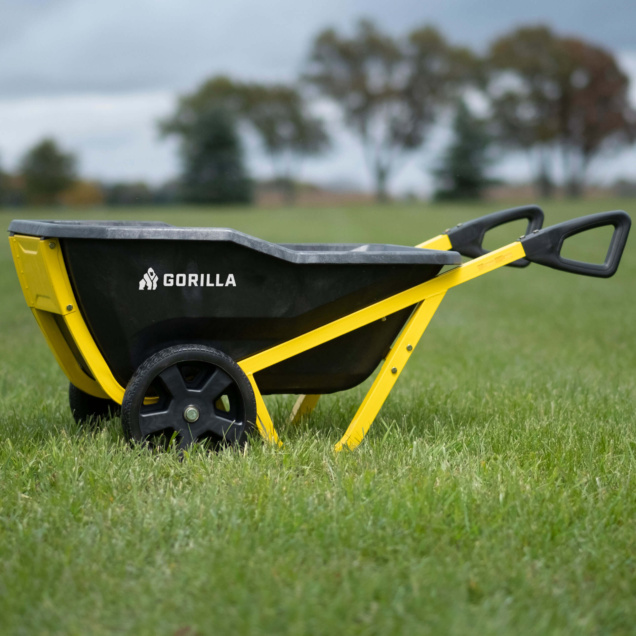 Gorilla Made wheelbarrow with black tub and yellow handles on grass.