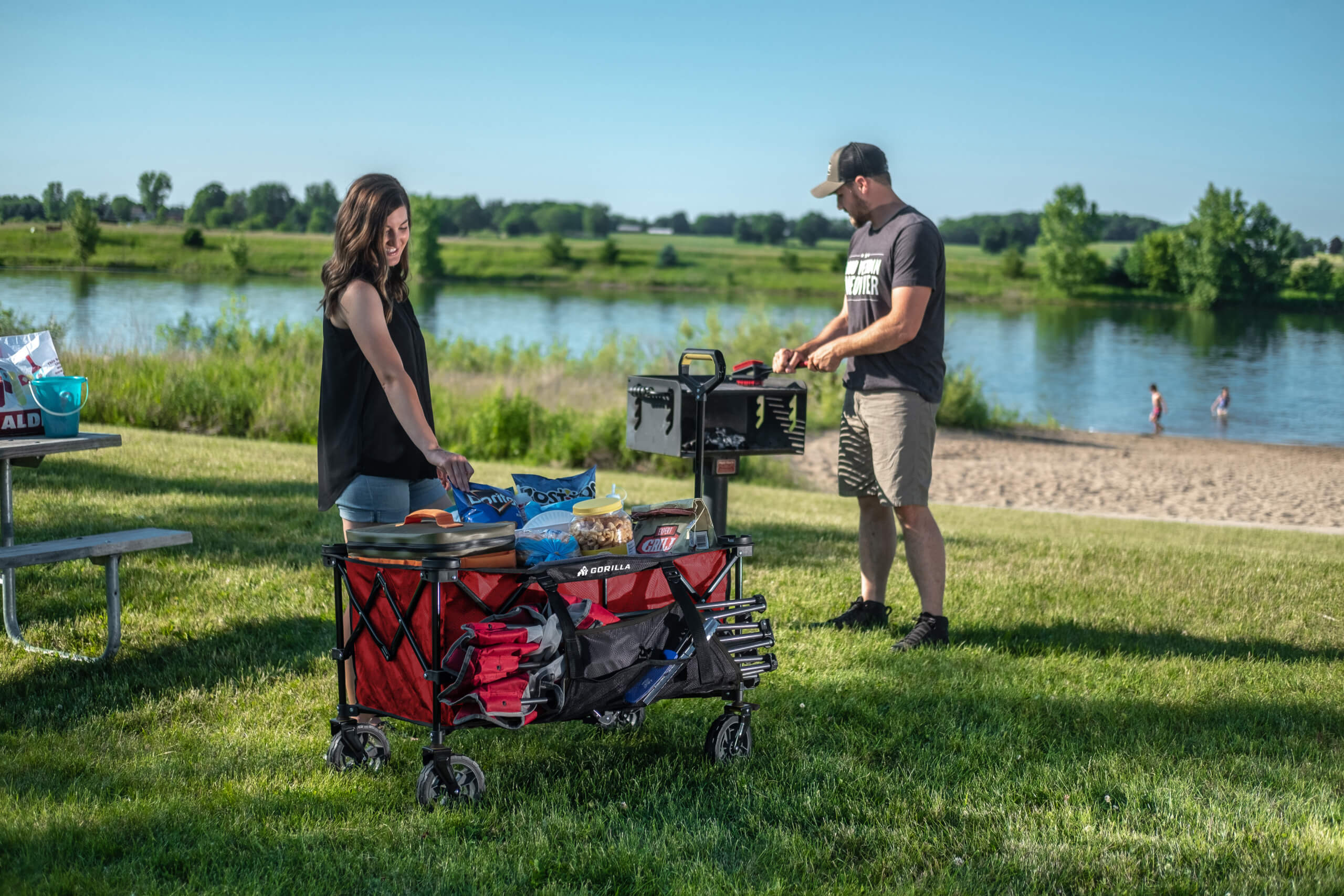 Red Gorilla Made cart loaded with items, near a picnic by the lake.