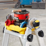 Yellow and silver Gorilla Made ladder with paint items. Text: "BEHR PREMIUM PLUS®".