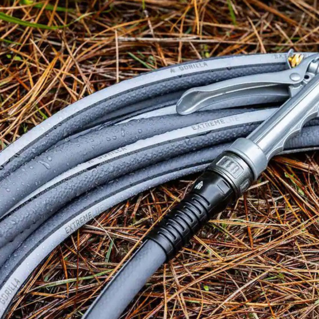 Coiled gray garden hose labeled "A Gorilla Extreme Lite" on pine needles.