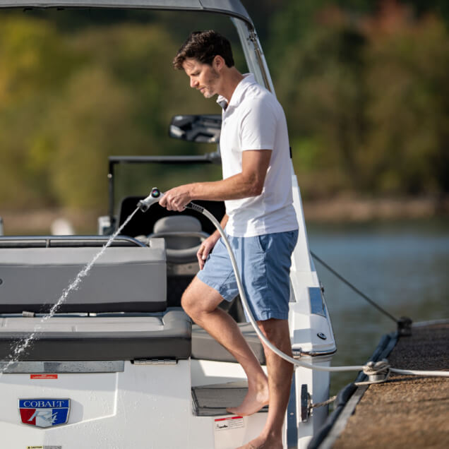 Person on a boat using a Gorilla Made garden hose with a Cobalt logo visible.