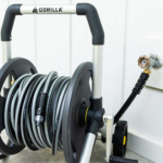 Gorilla hose reel with gray hose, black handle, connected to faucet.