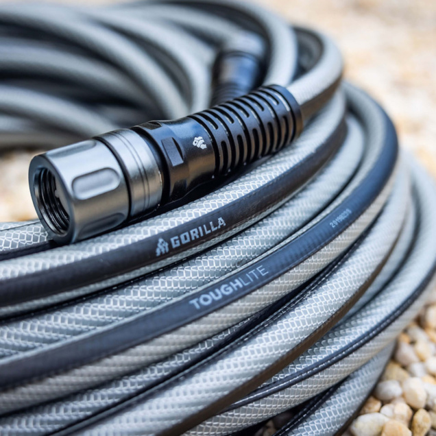 Close-up of a coiled gray ToughLite hose with black nozzle, branded "GORILLA."