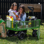 Green Gorilla cart with gardening supplies and two people planting in pots.