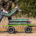 Green Gorilla cart loaded with bags of "Dark Brown Majestic Mulch," outdoors.