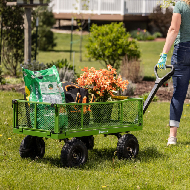 Green Gorilla Made utility cart carrying soil bag, flowers, and tools in a garden.