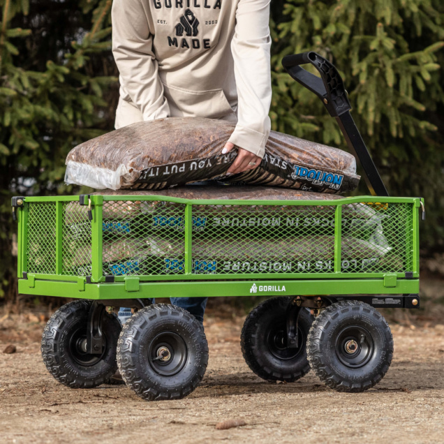 Person loading mulch onto a green Gorilla Made cart with "Gorilla" logo visible.