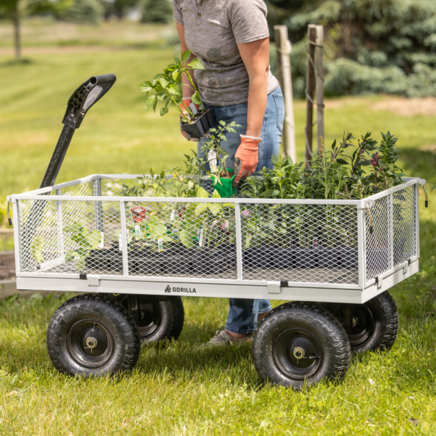 Person with plants in heavy-duty Gorilla Made metal mesh cart on grass.