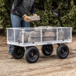 Person loading bricks into a white Gorilla utility cart with black wheels on dirt ground.
