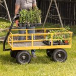 Person moving plants with a yellow Gorilla utility cart on grassy lawn.