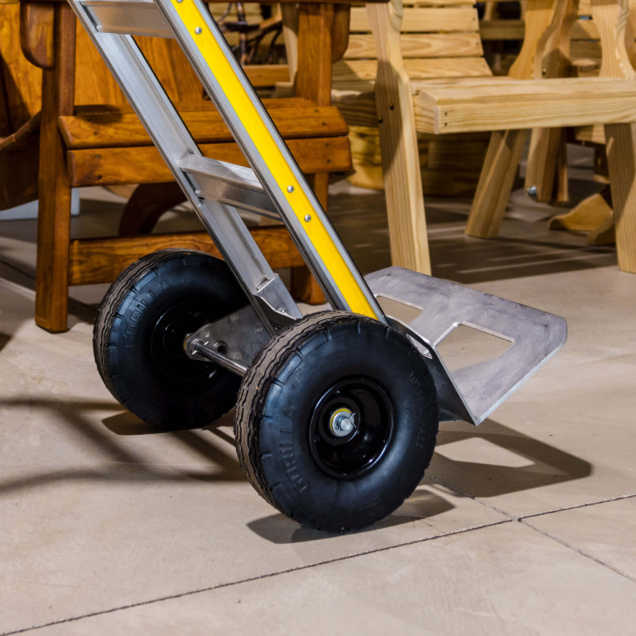 Hand truck with a yellow frame and sturdy black tires on a concrete floor.