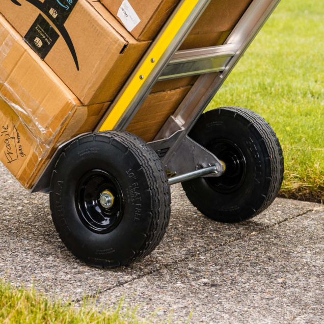 Close-up of Gorilla Made hand truck with black tires, yellow frame, carrying boxes marked "Fragile."