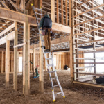 Person climbing a silver Gorilla Made ladder in a wooden construction site.