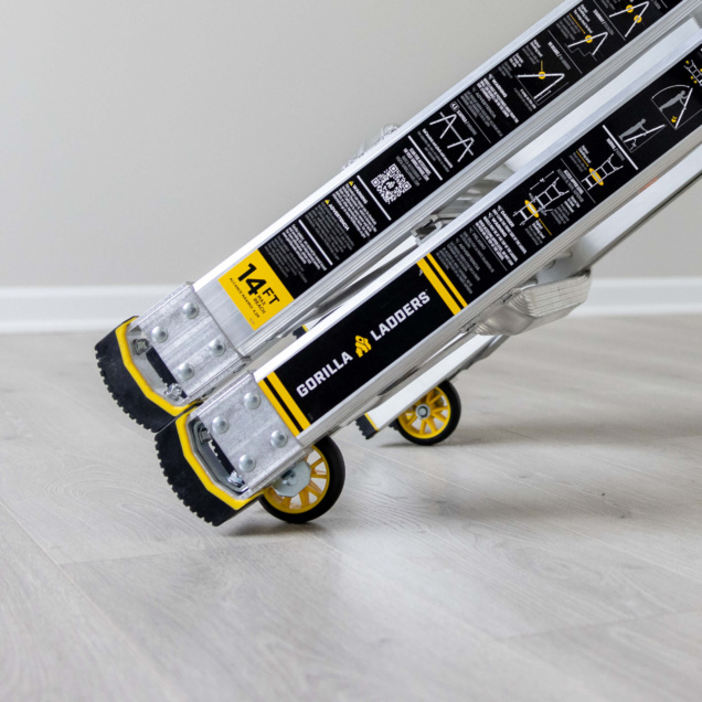 Silver Gorilla Ladders with yellow accents, labeled "14 FT", on a light wood floor.