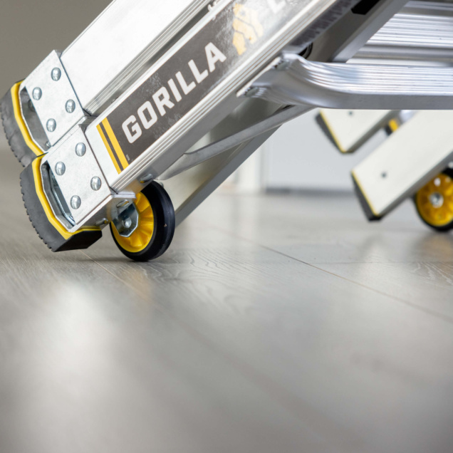 Close-up of a Gorilla Made ladder with yellow accents and wheels on a wooden floor.