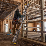 Person using a Gorilla Made ladder with yellow accents in a wooden construction site.