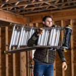 Person holding a silver Gorilla Ladders ladder in a construction setting.