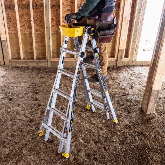 Worker on a Gorilla Made ladder with yellow accents inside a wooden-framed structure.