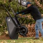 Man using black Gorilla Made wheelbarrow on grass. GPXD 6C logo visible.