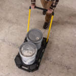 Gorilla Made cart carrying two grey paint buckets. Yellow handles, tiled floor.