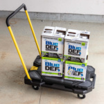 Black cart with yellow handle carrying Blue DEF Platinum Diesel Exhaust Fluid boxes.