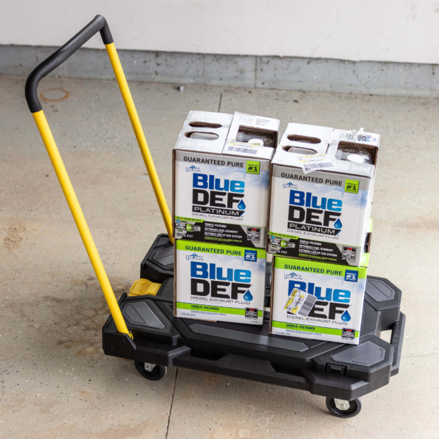 Black cart with yellow handle carrying Blue DEF Platinum Diesel Exhaust Fluid boxes.