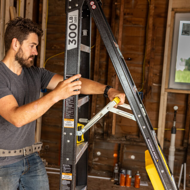 Person using a Gorilla Made ladder marked "300 LB LOAD" in a construction setting.