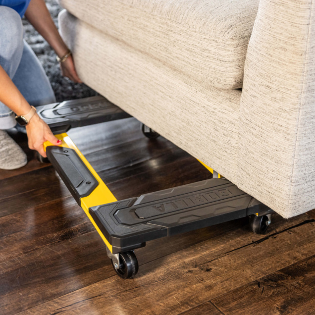 A yellow and black Gorilla Made furniture dolly used to move a beige sofa.