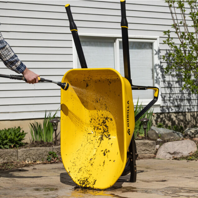 Yellow Gorilla wheelbarrow being rinsed, "GORILLA" text visible on the side.