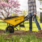 Yellow Gorilla wheelbarrow filled with mulch, featuring flat-free tire in a garden.