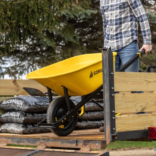 Yellow Gorilla Made wheelbarrow on a trailer with black mulch bags.