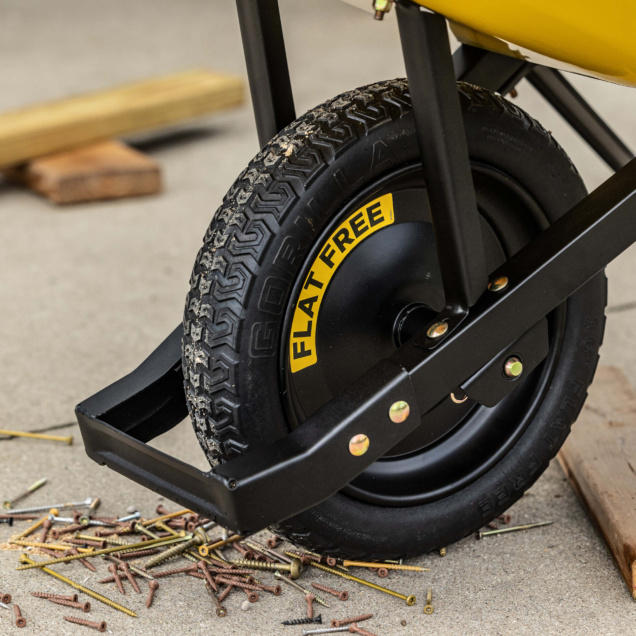 Black wheelbarrow tire with "Flat Free" text, surrounded by scattered screws.